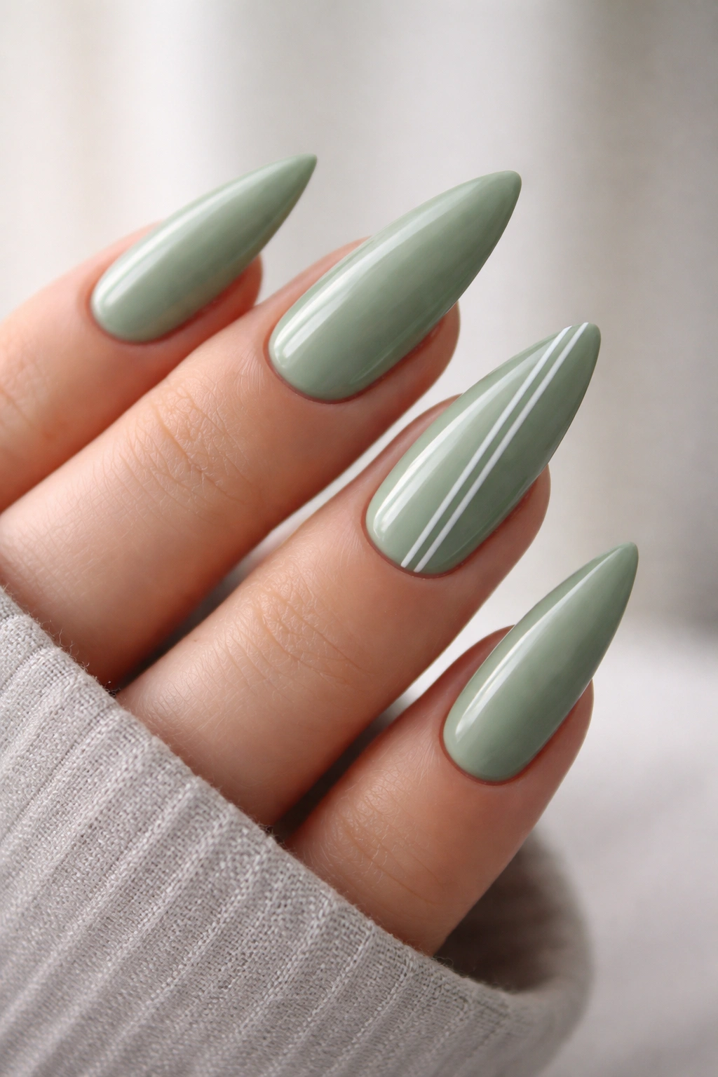 Sage green stiletto nails with white minimalist line work on accent nails