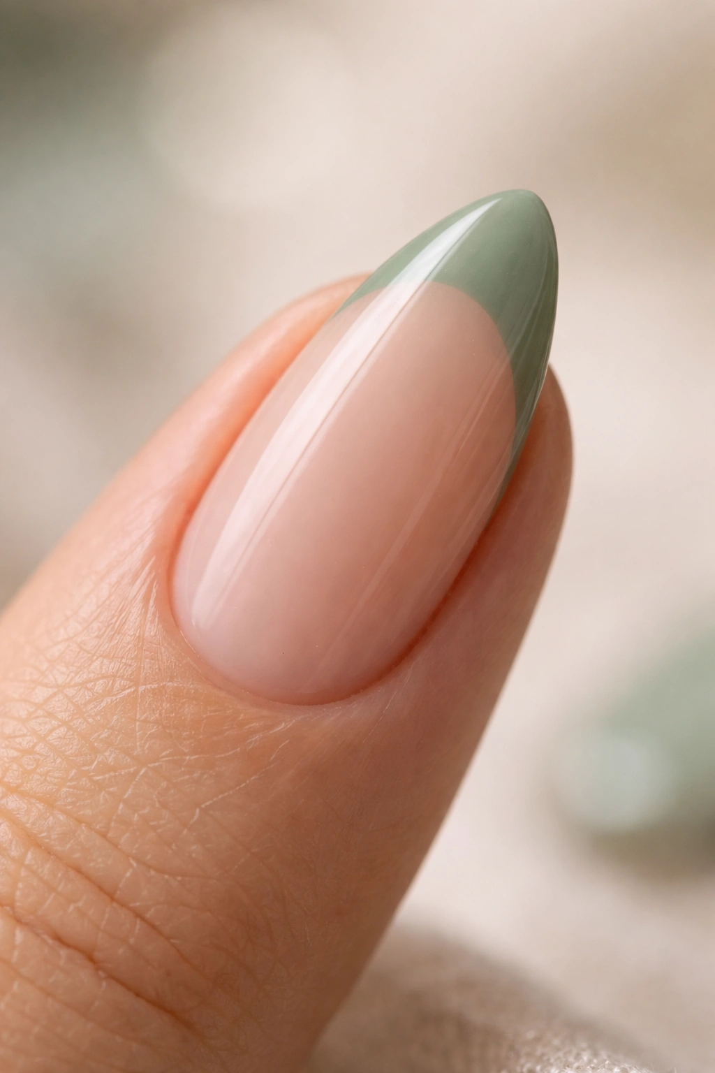 Almond nail with desaturated sage green polish on sheer base
