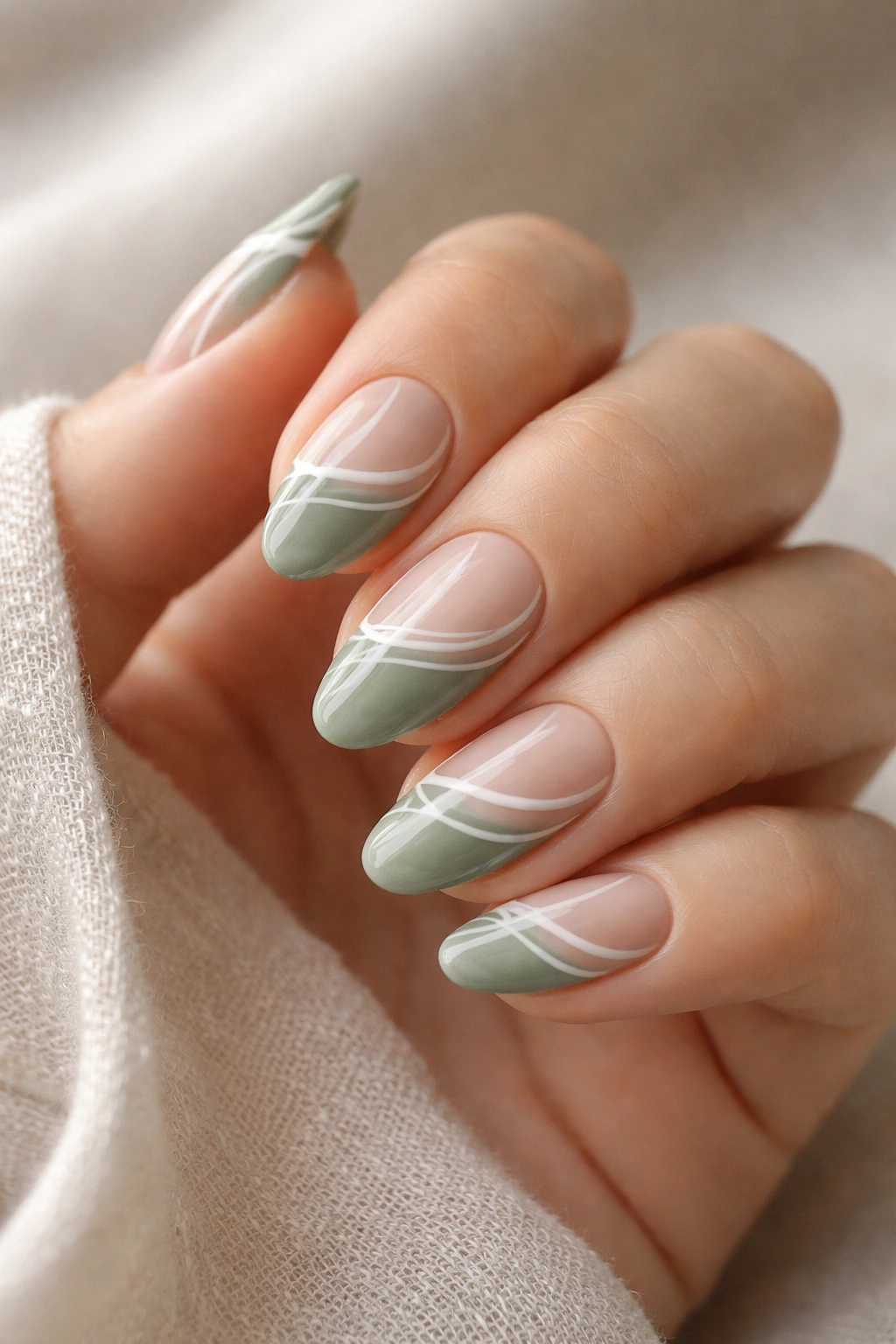 Close-up of sage nails with white swirling line art on tips