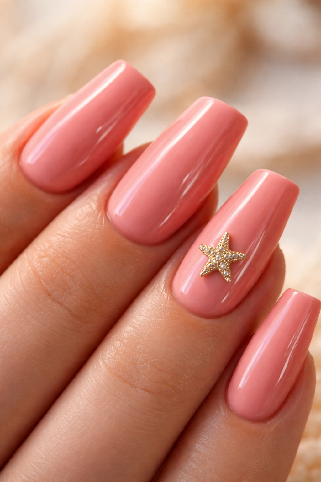 Salmon pink nails with a tiny starfish charm on one nail