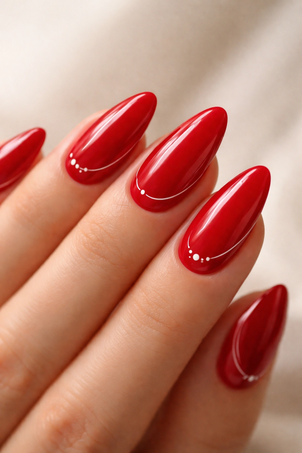 Close-up of scarlet red almond nails with tiny white micro-details