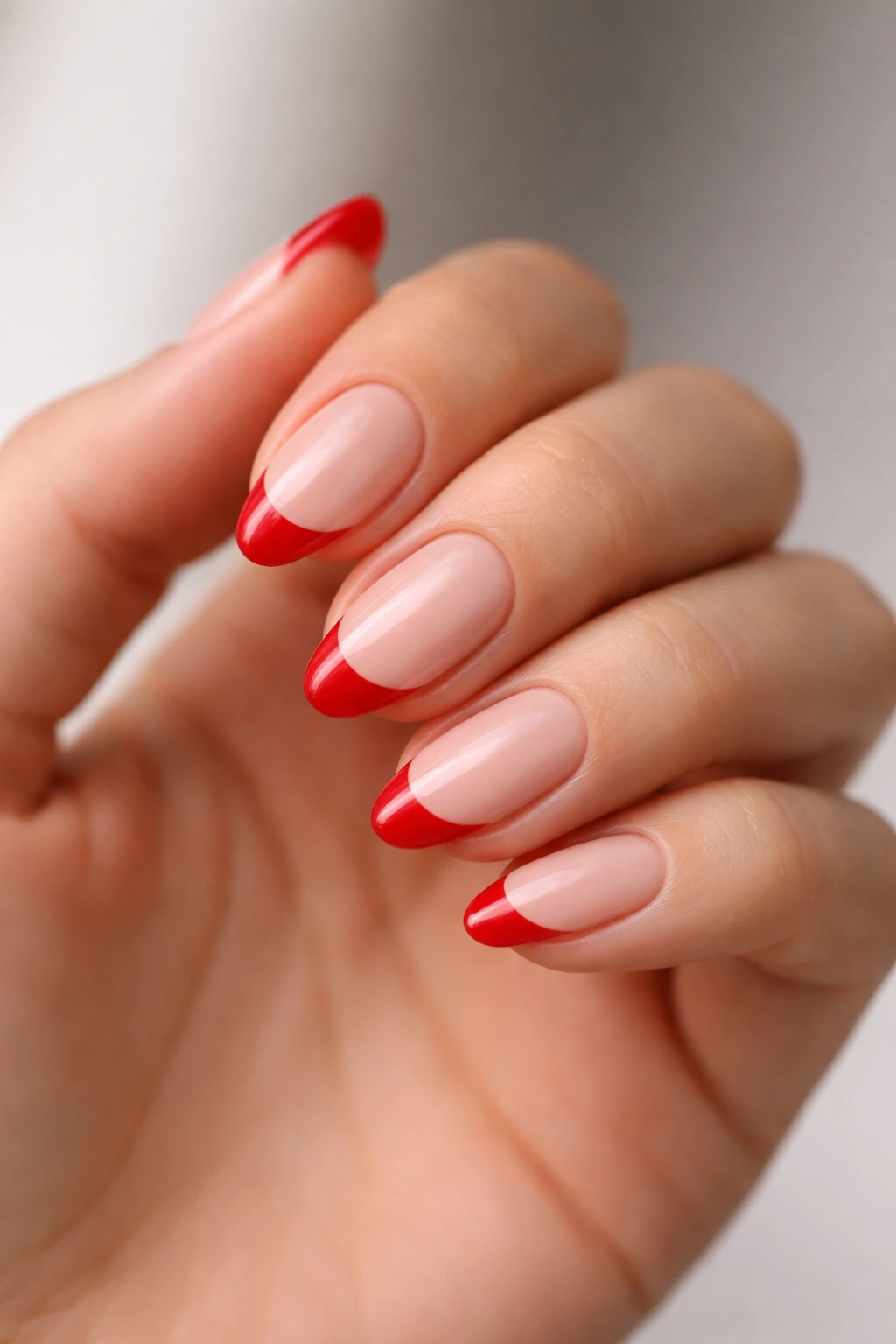 Close-up of short almond nails with scarlet tips