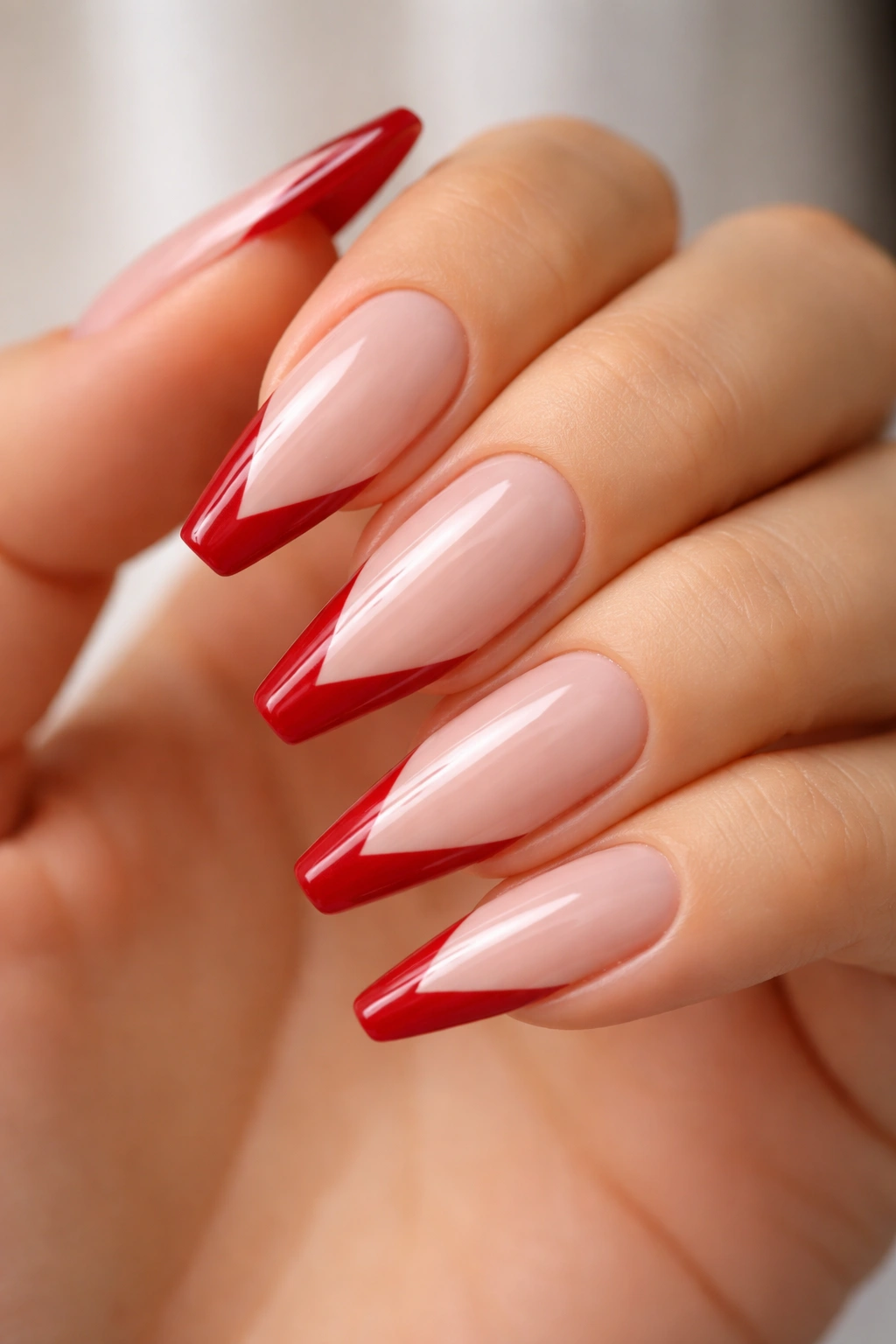 Nails with scarlet V-cut French tips on milky beige base
