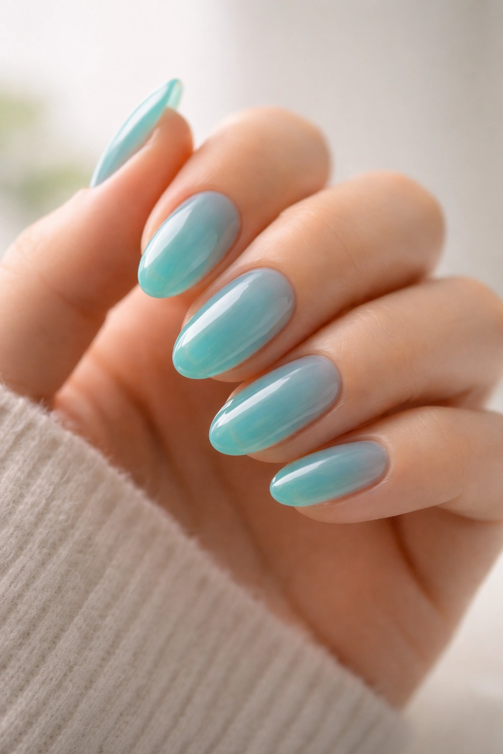 Close-up of a hand with short almond sea glass turquoise nails in translucent jelly finish