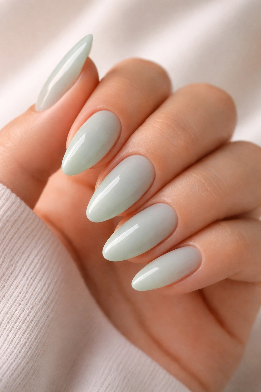 Close-up of seafoam almond nails with a glossy finish showing translucent pastel green.
