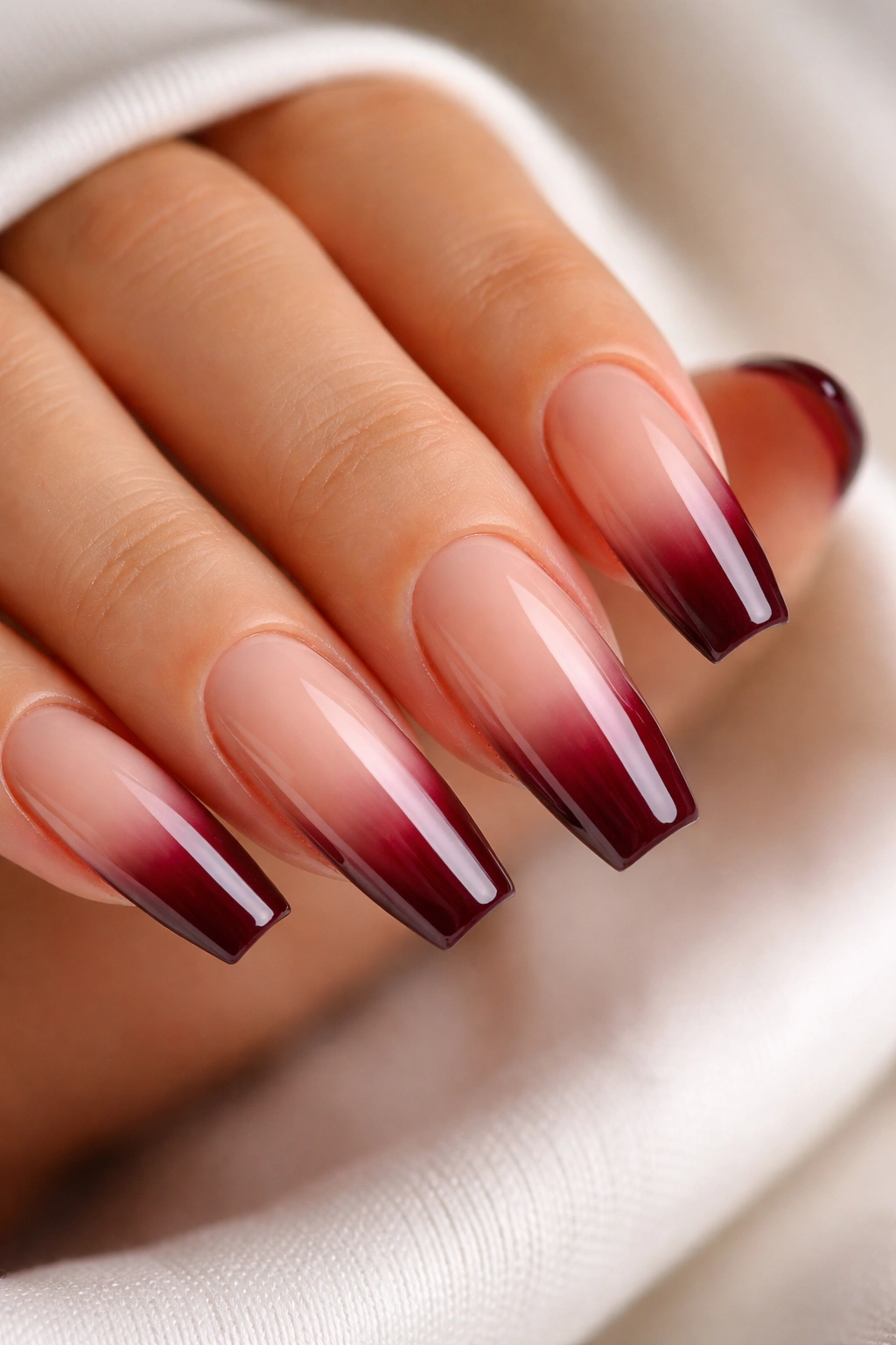 Nails with sheer nude base and burgundy tip gradient edge