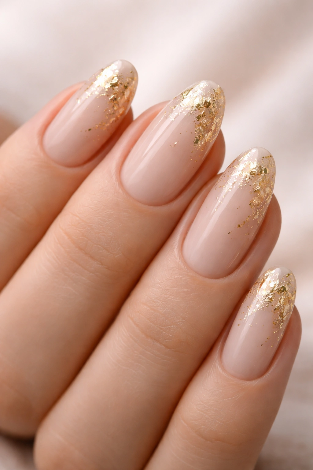 Nails with sheer beige polish and gold foil accents