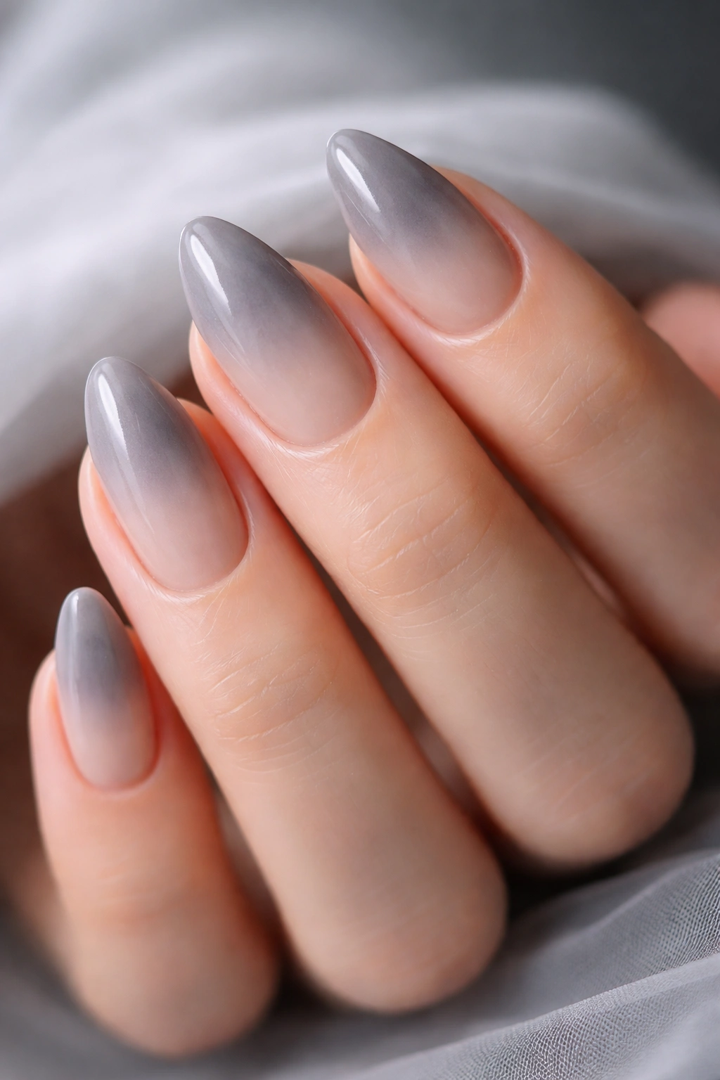 Close-up of short almond nails with sheer gray smoke over nude base