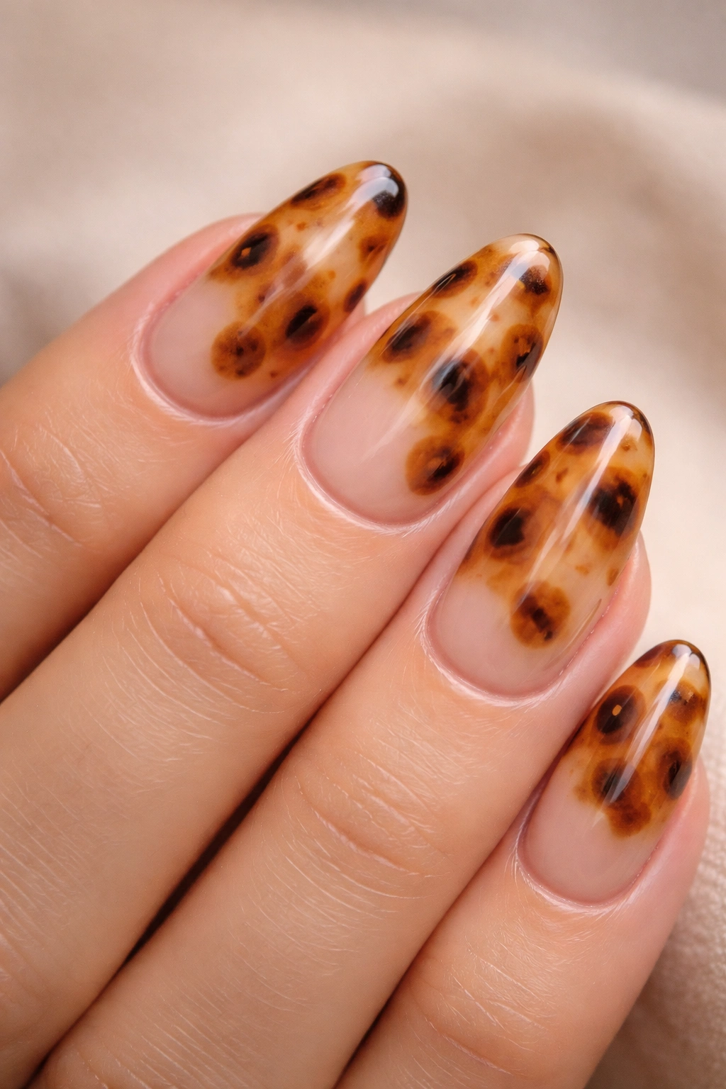 Close-up of short almond nails with sheer honey tortoiseshell on milky nude base