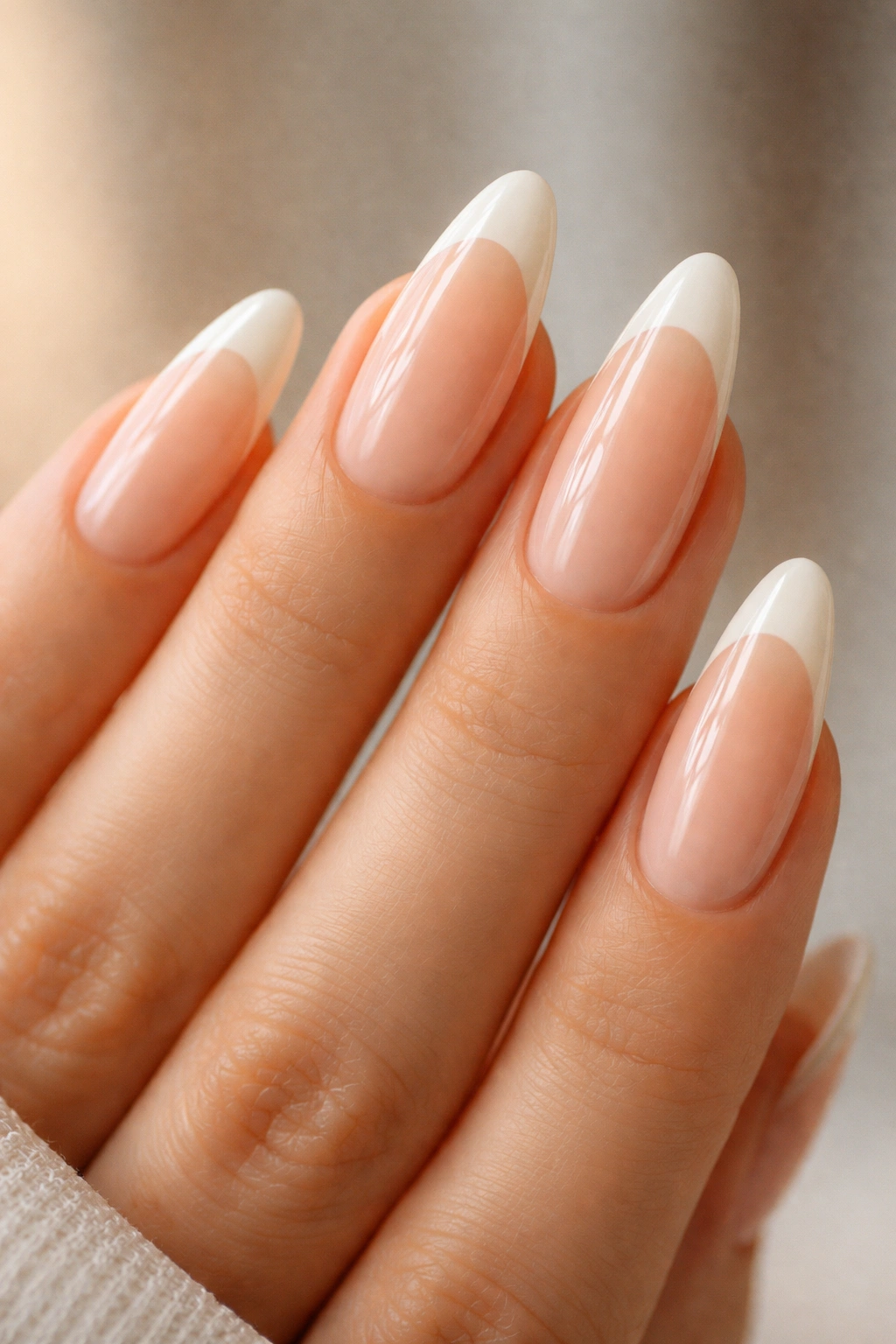 Almond nails with sheer peach base and ivory tips on a warm background