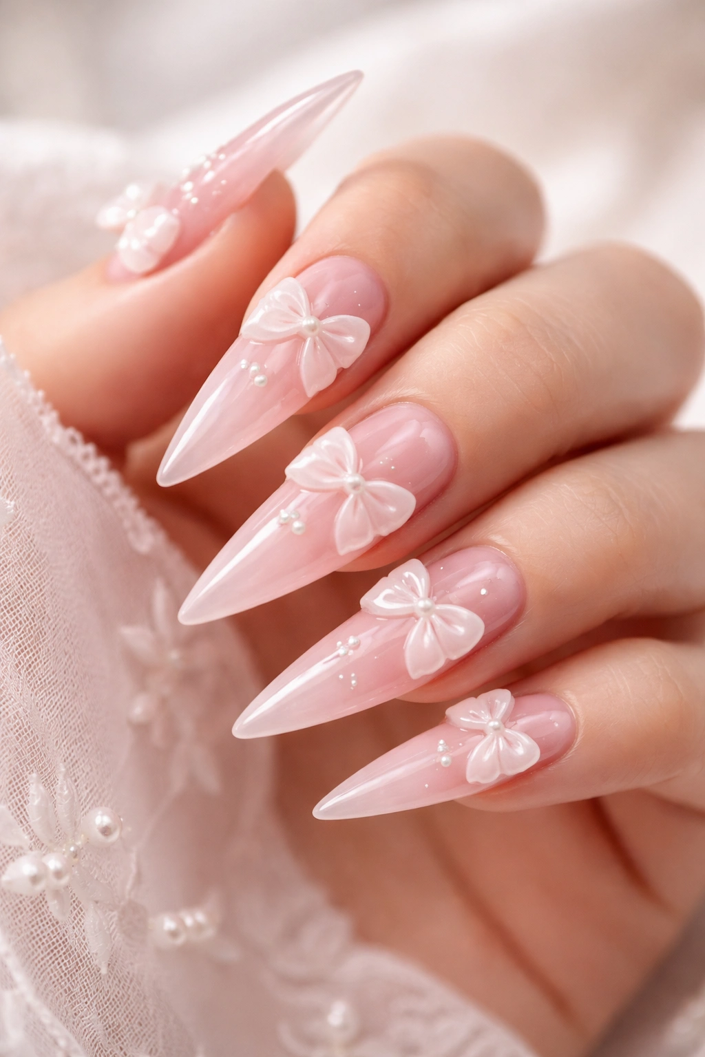 Close-up of a sheer pink stiletto nail with 3D bows
