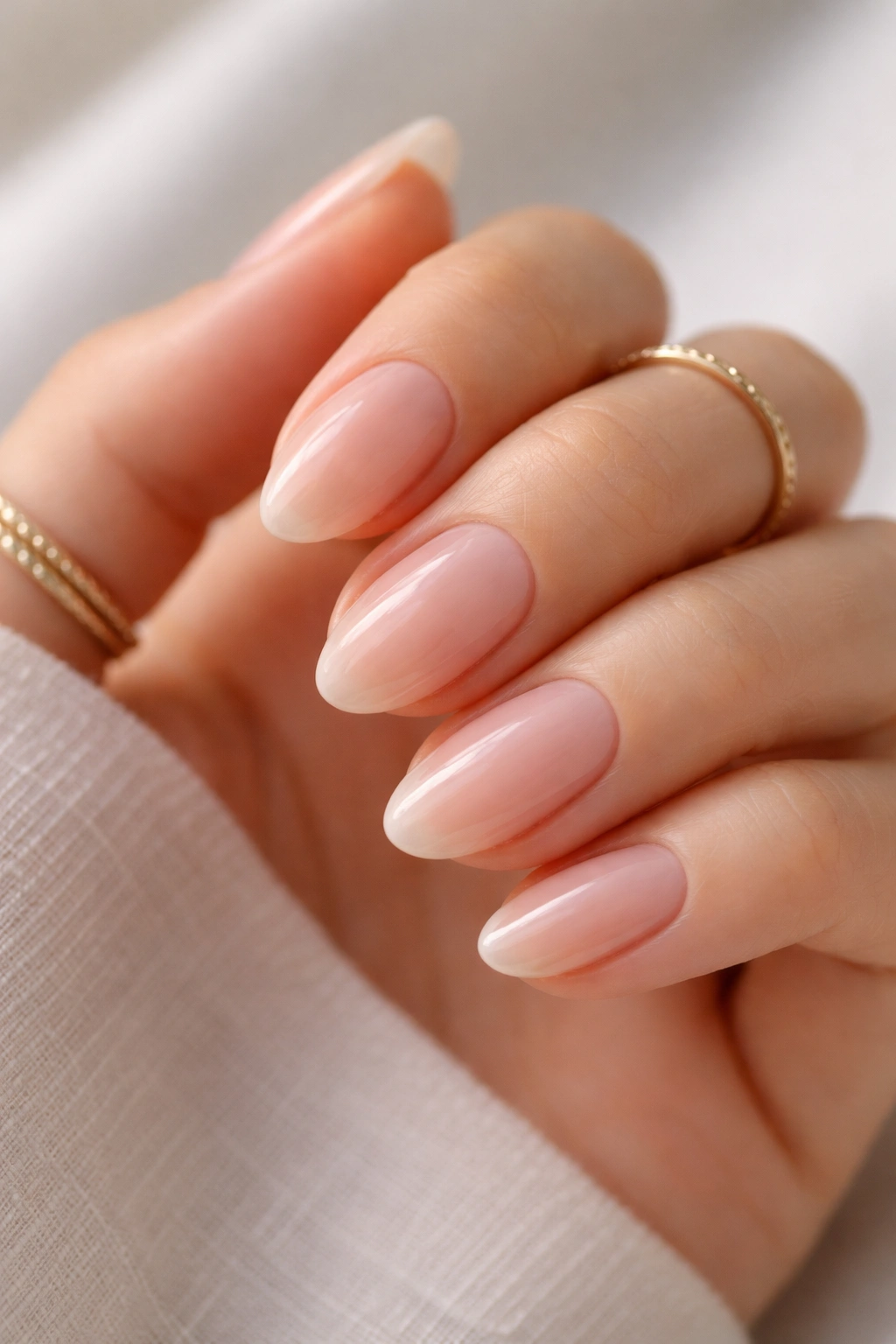Close-up of sheer pink nails with barely-there tips on short almond shape