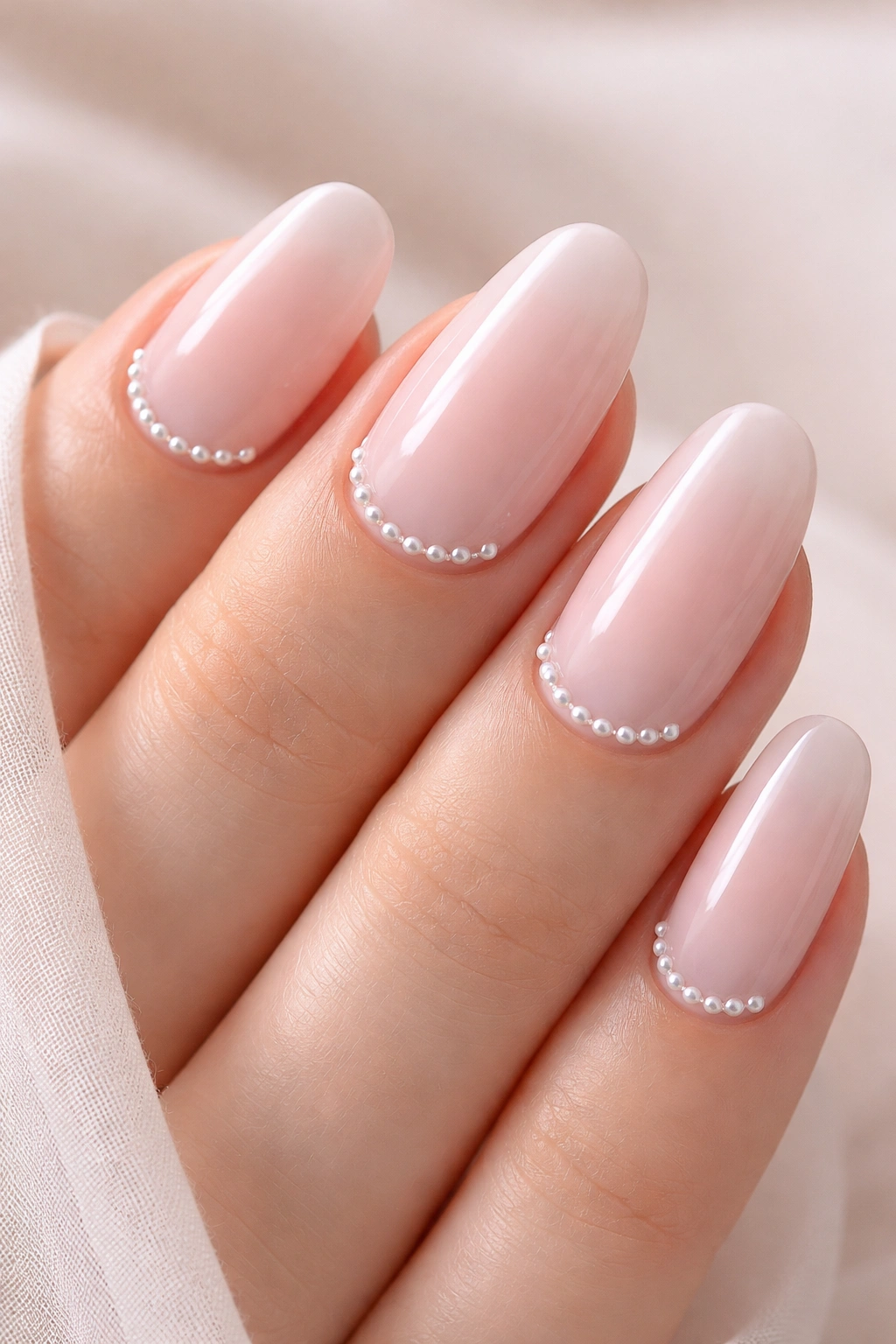 Close-up of sheer pink nails with minimalist pearl accents