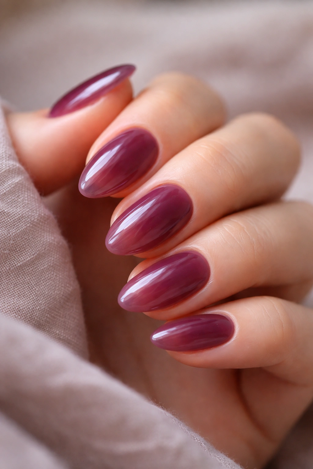 Close-up of short almond nails with sheer plum jelly finish