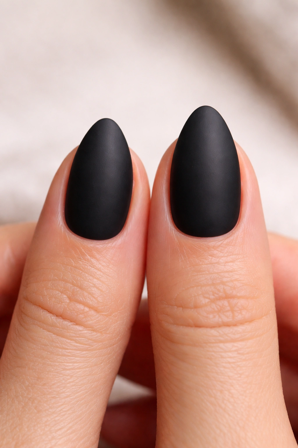 Hand displaying two short almond nails of different lengths to compare options