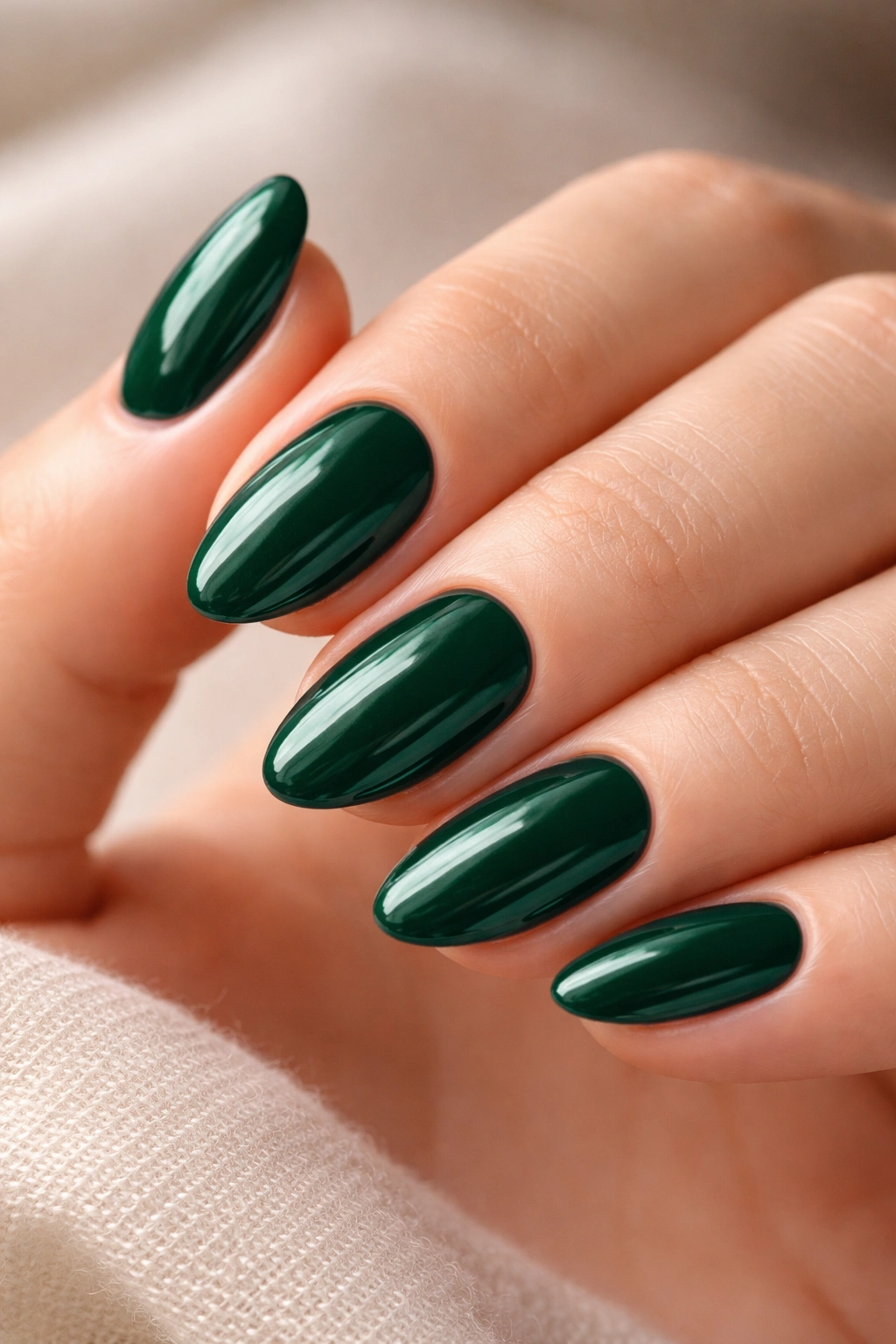 Close-up of short almond nails with neat emerald polish and clean edges
