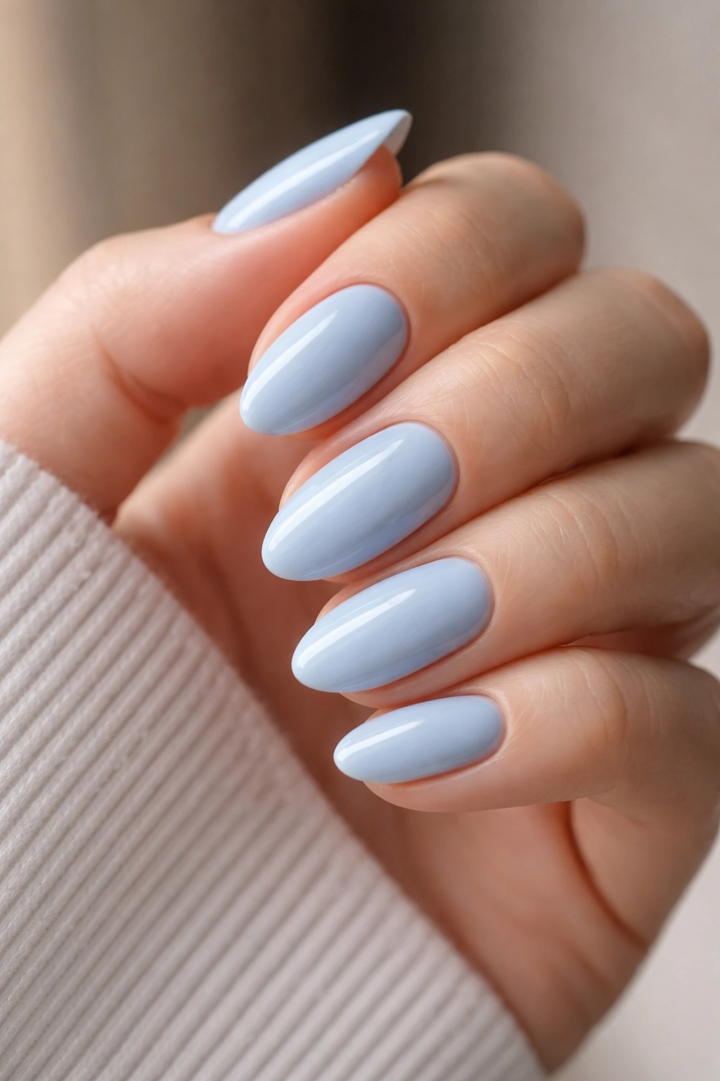 Close-up of short almond nails with glossy blue polish and clean cuticles.