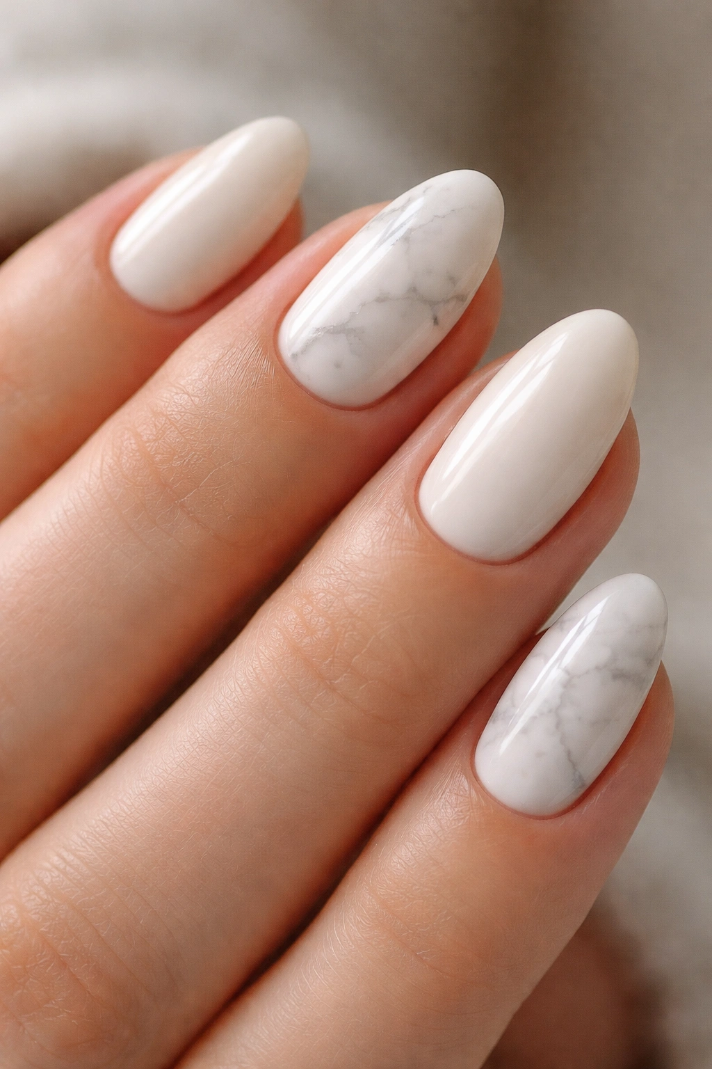 Close-up of short almond nails with soft white marble veining