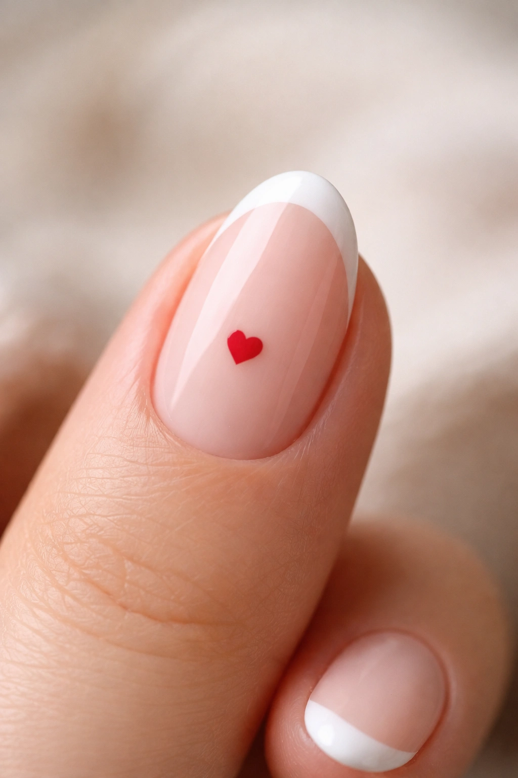 Ultra-short almond nail with tiny heart accent and crisp French tip macro shot