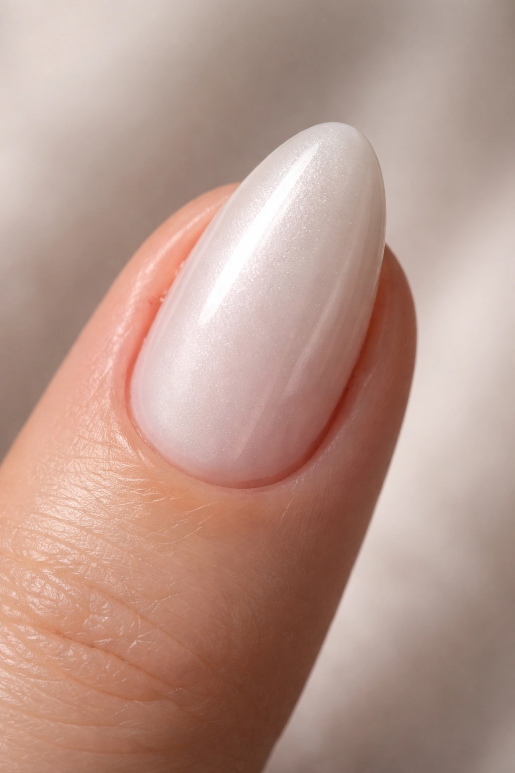 Close-up of a short almond nail with pale pearl-white finish