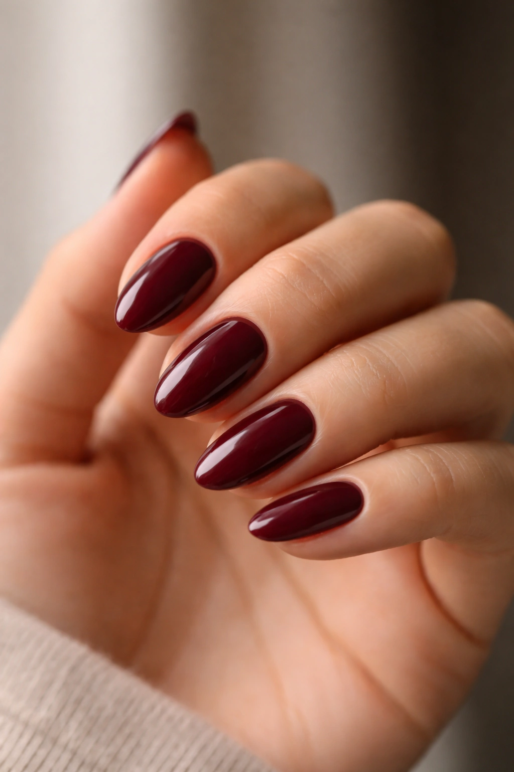 Close-up of short almond nails with maroon polish showing shape and length