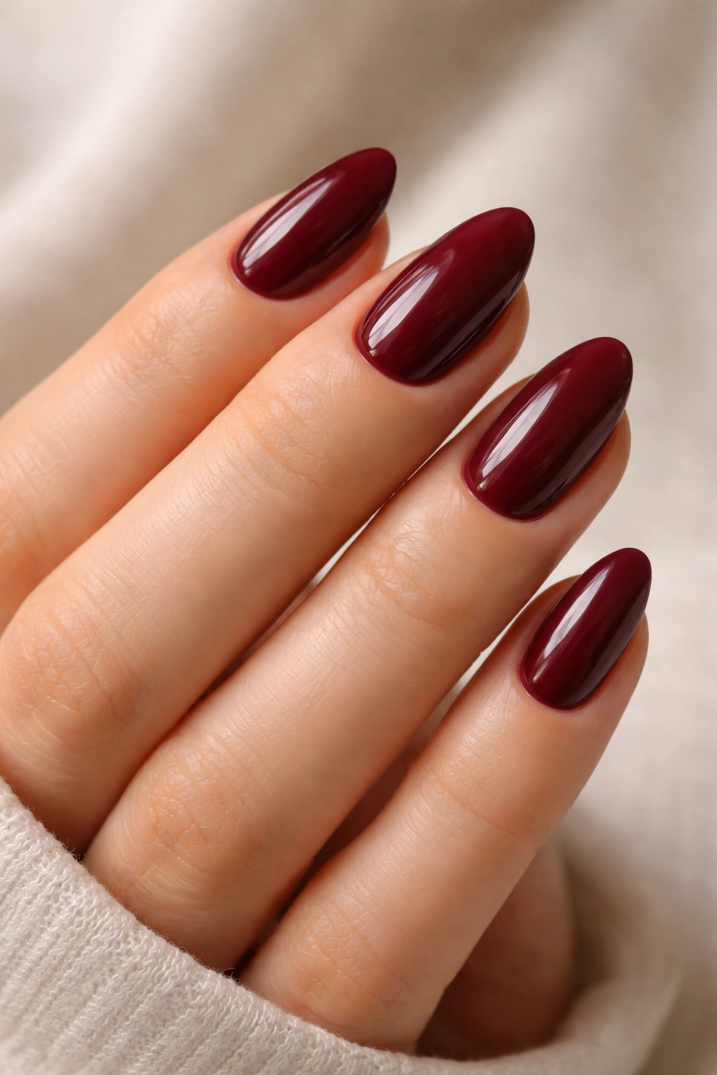 Close-up of short almond burgundy nails showing gentle taper and curved sides