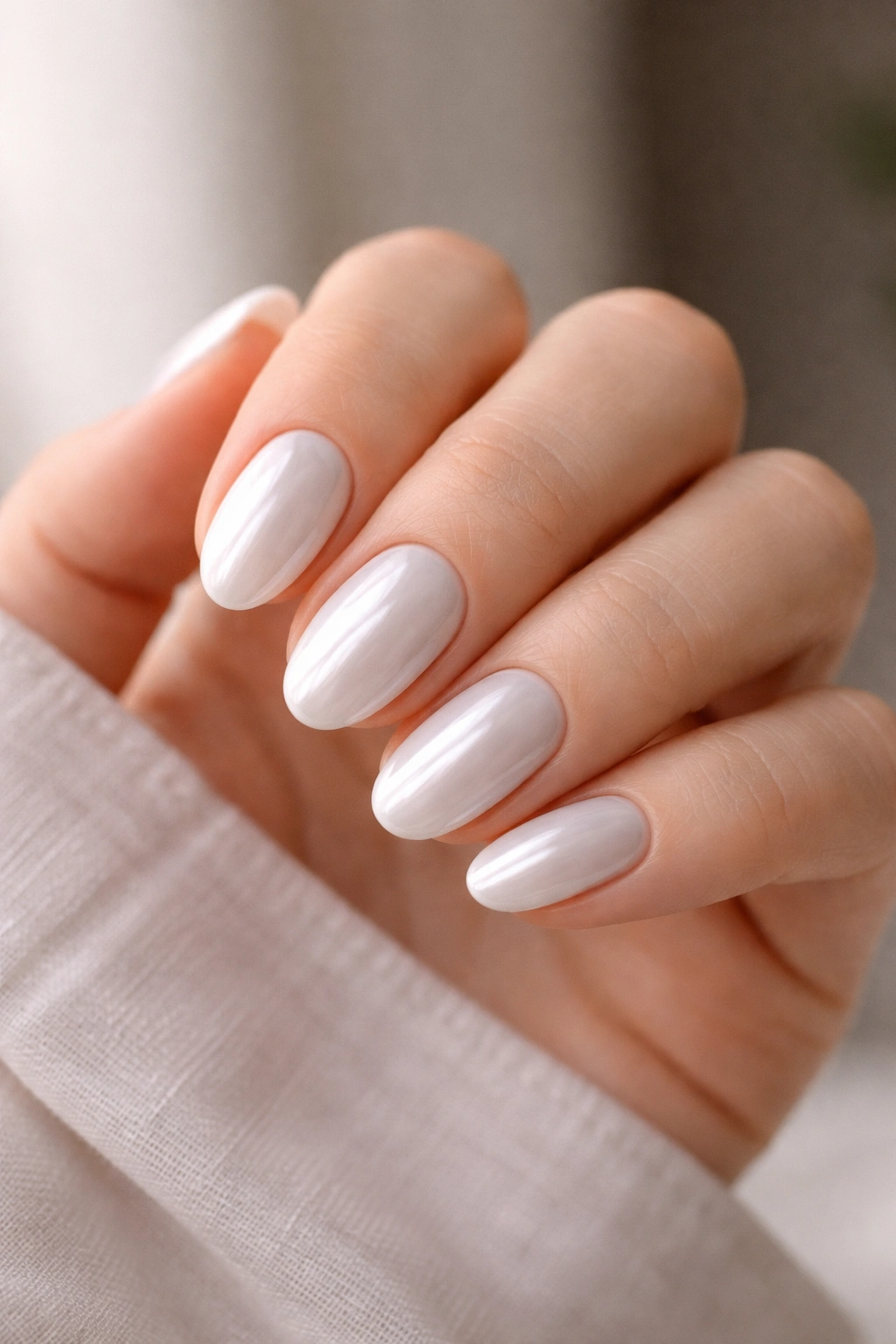 Hand with short almond nails in fresh white chrome shine