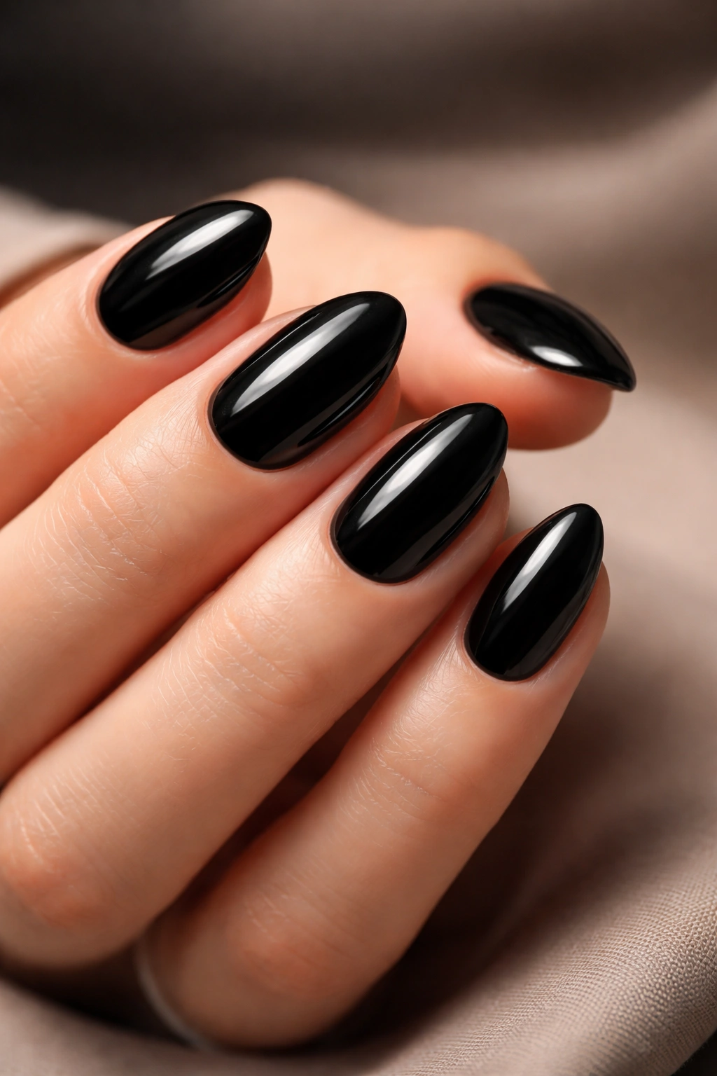 Close-up of short black almond nails with glossy finish and precise cuticles