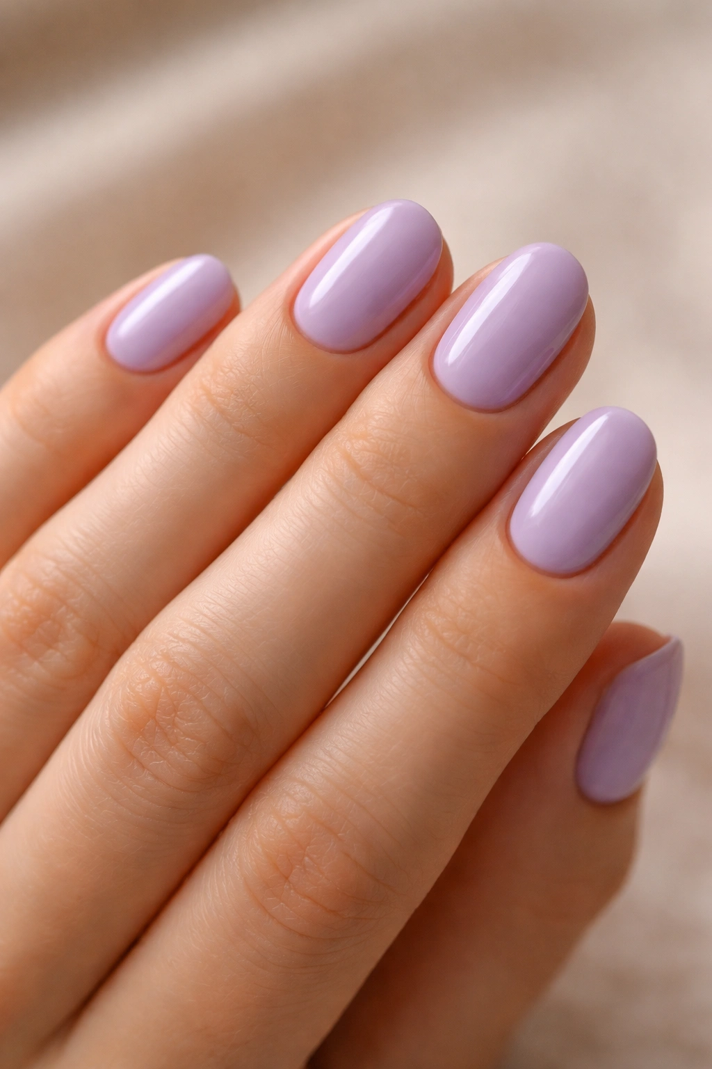Close-up of short oval lavender nails with neat cuticles on a hand