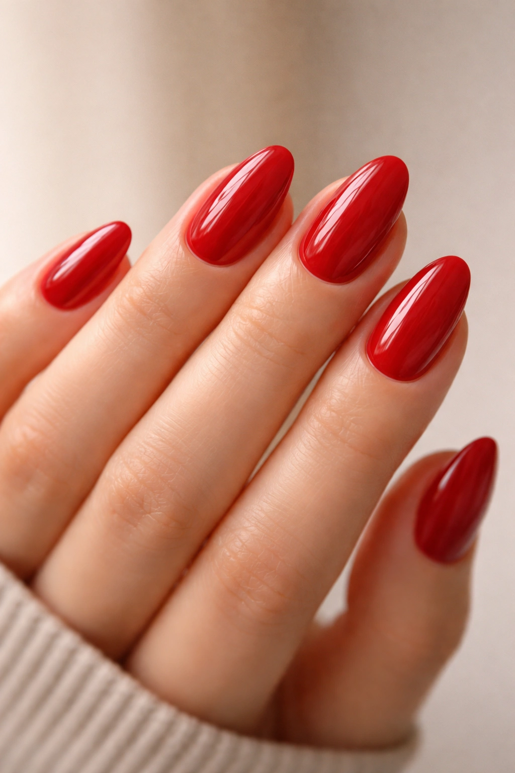 Close-up of short almond nails with a high-gloss clear overlay on red polish