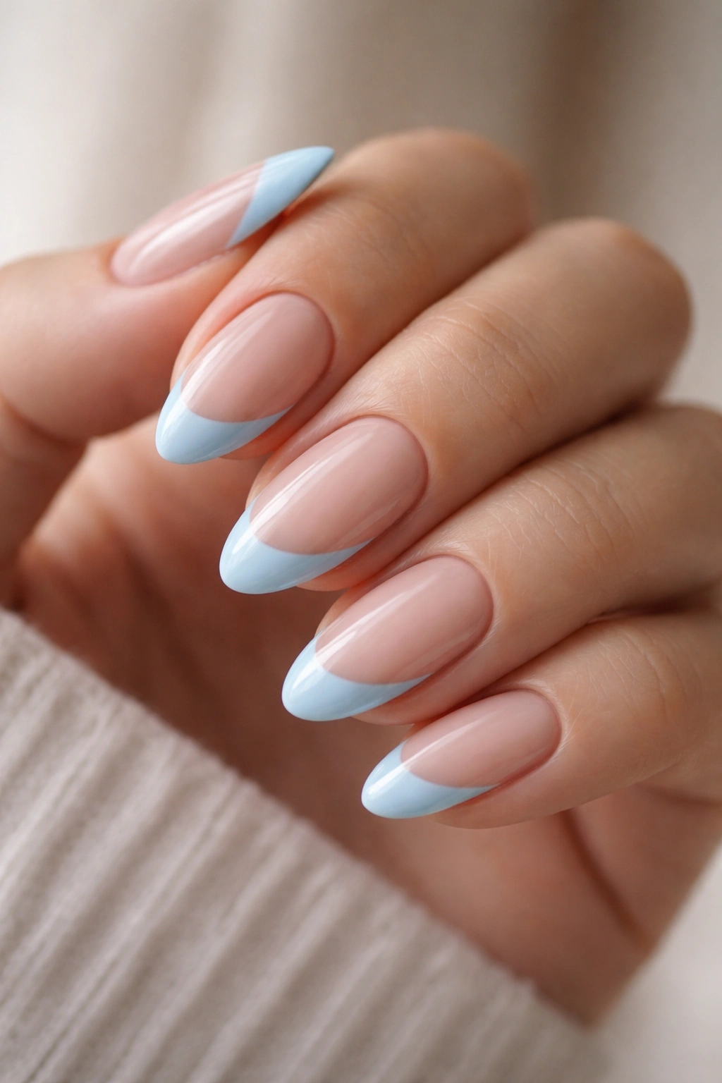 Close-up of short almond nails with side-swept blue French tips