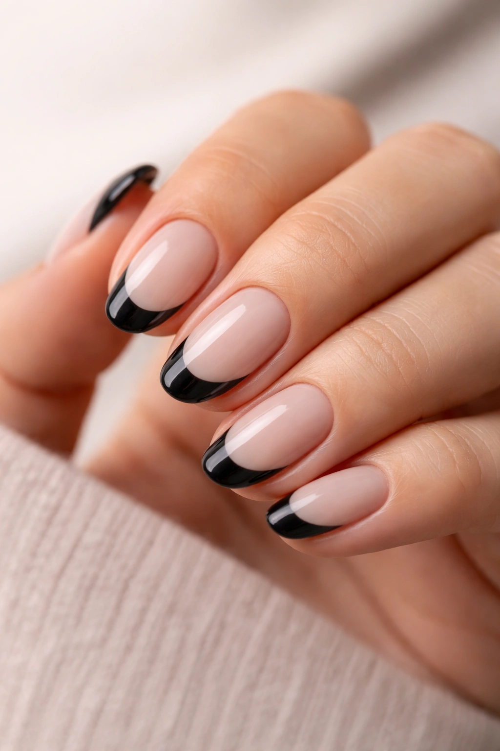 Close-up of short oval nails with diagonally side-swept black tips