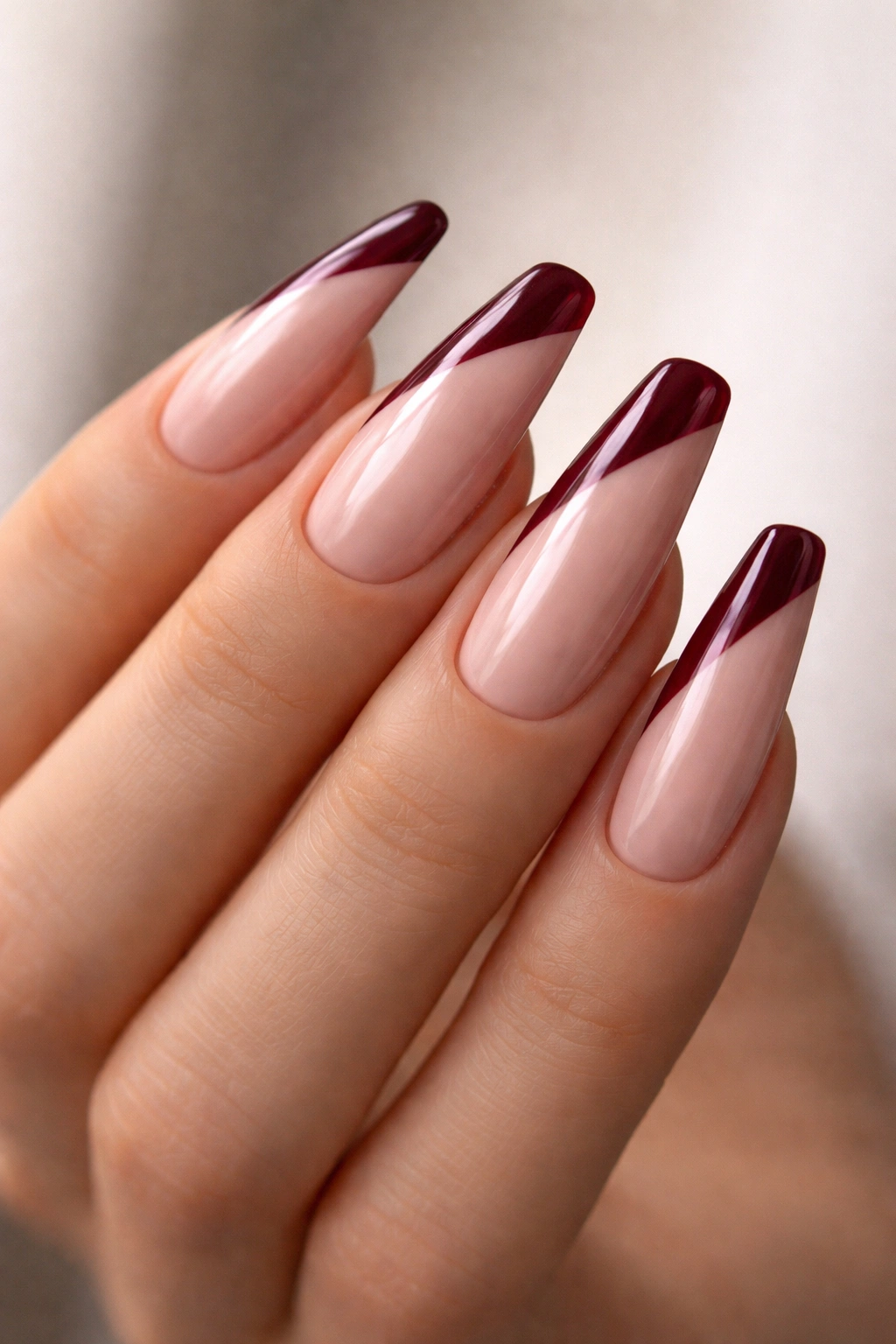 Side-swept wine red French tips on nude base nails