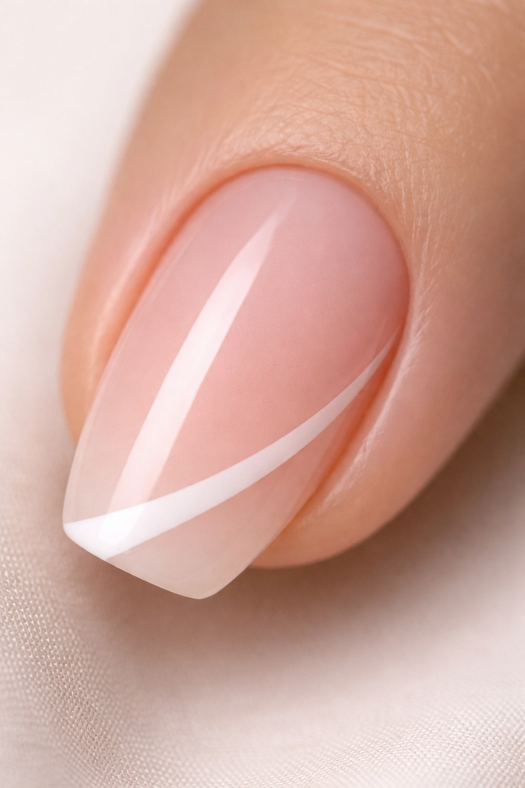 Close-up of a short ballerina nail with a diagonal white French tip on pink base