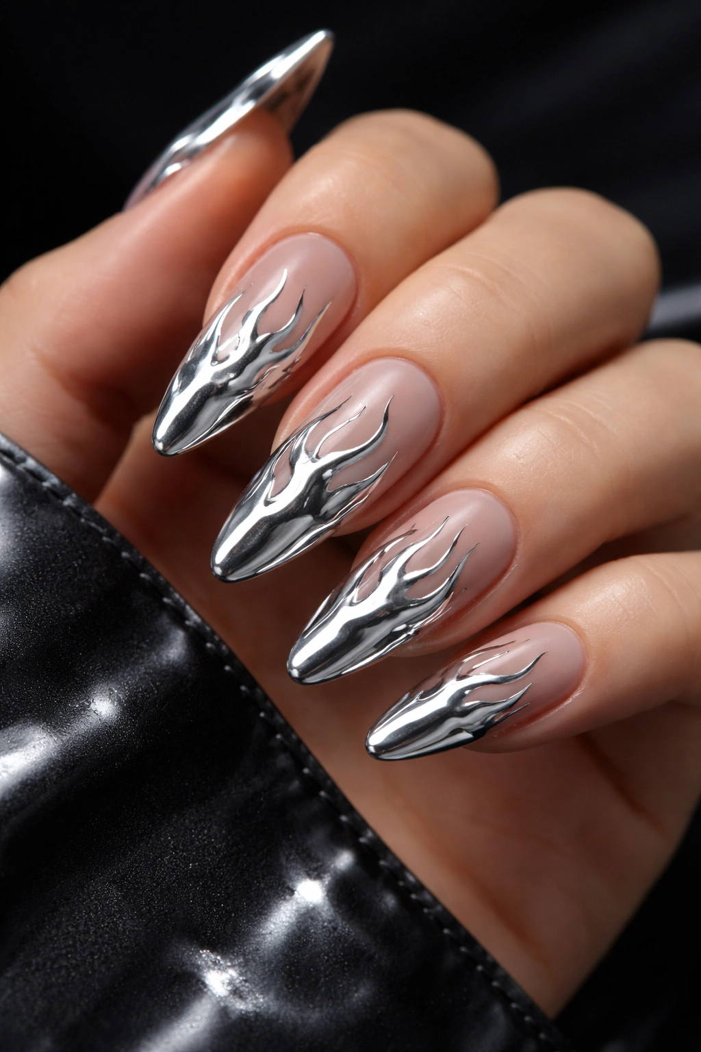 Close-up nails with silver chrome flame designs on dark background