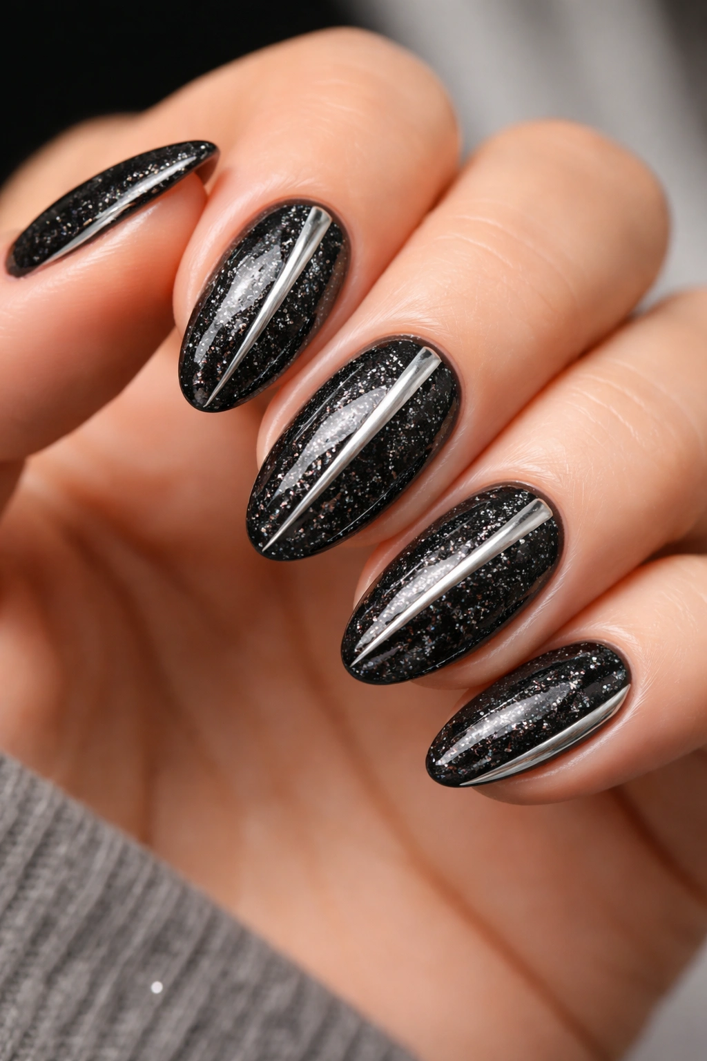 Short almond nails with black glitter and silver chrome accents