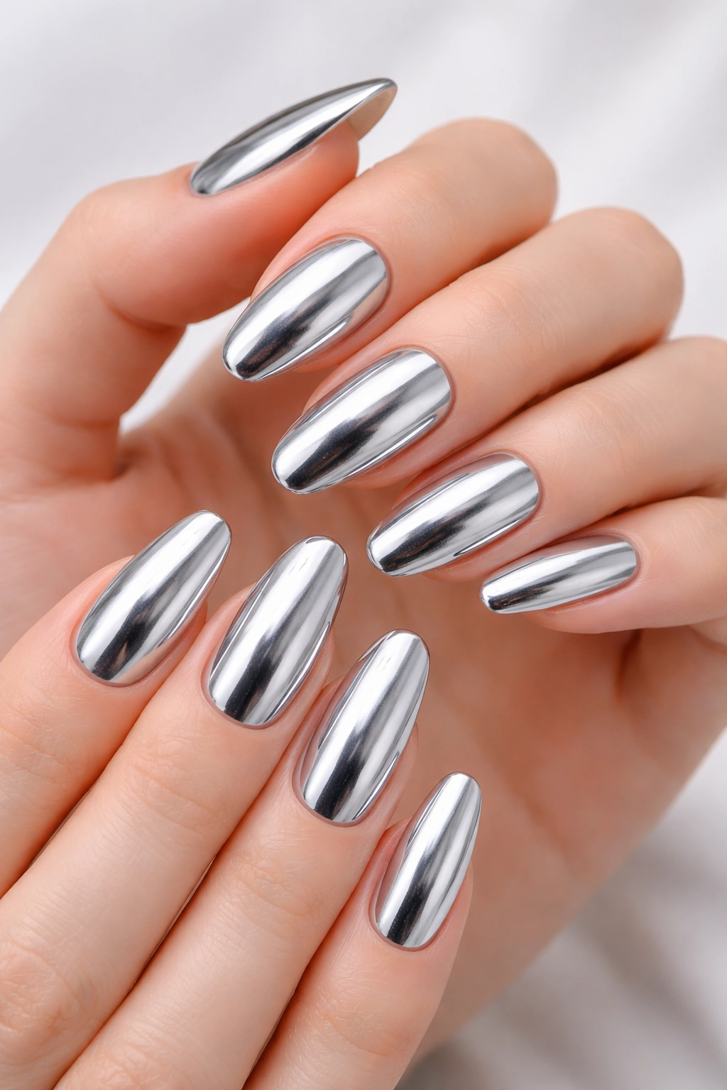Close-up of hands with full silver chrome nails reflecting studio light