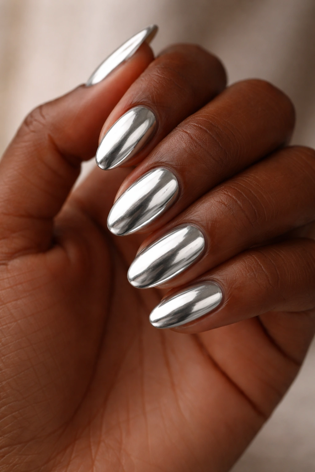 Close-up of silver chrome short almond nails on dark skin