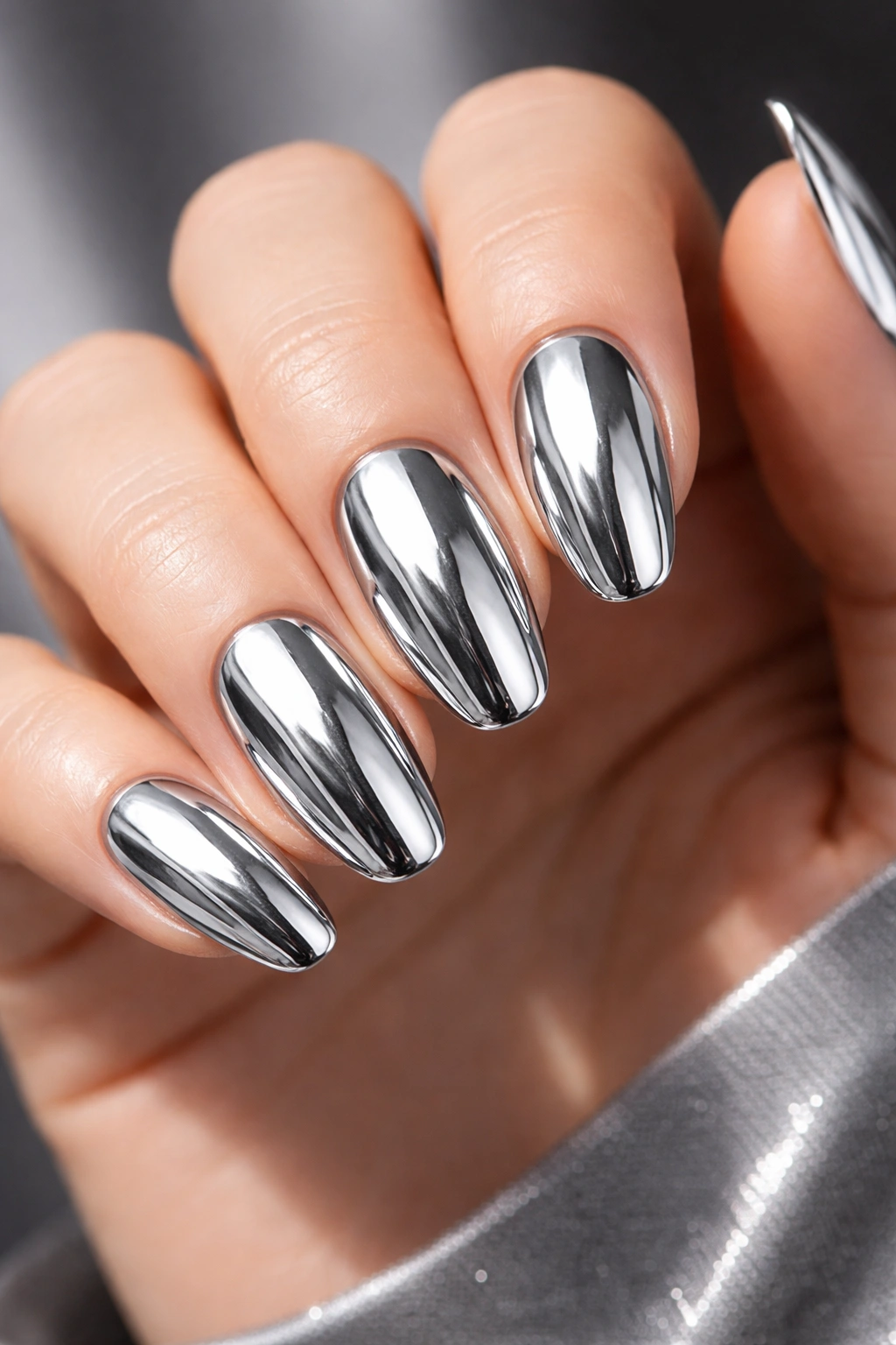 Close-up of hand with full silver chrome manicure showing mirror-like nails