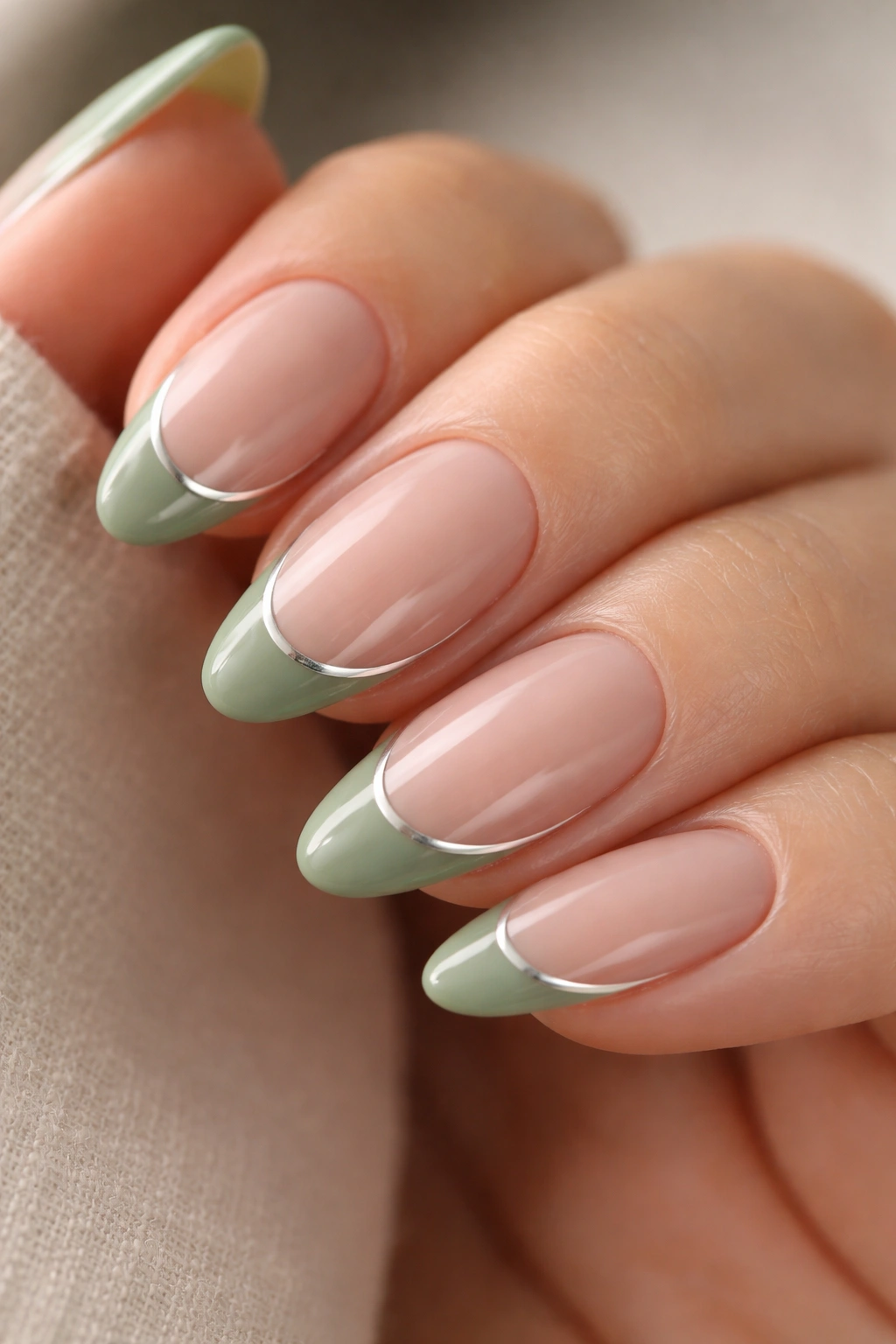 Short almond nails with a thin silver chrome line along the sage tip