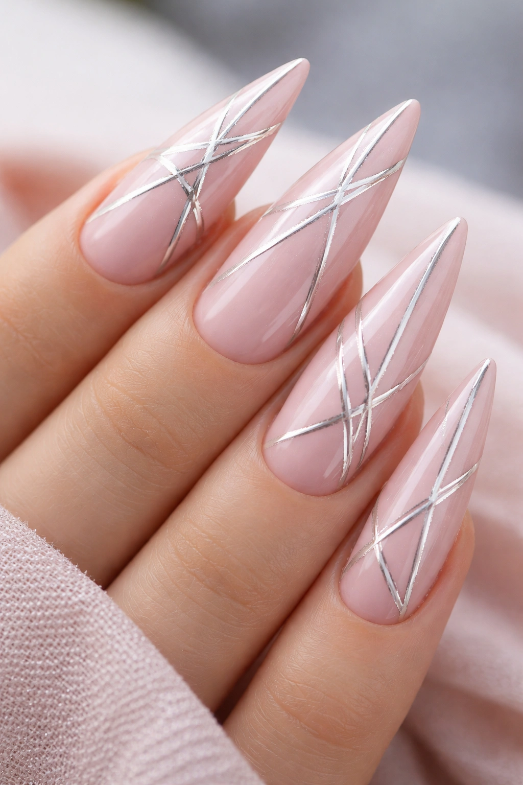 Stiletto nails with silver geometric lines on pale pink base