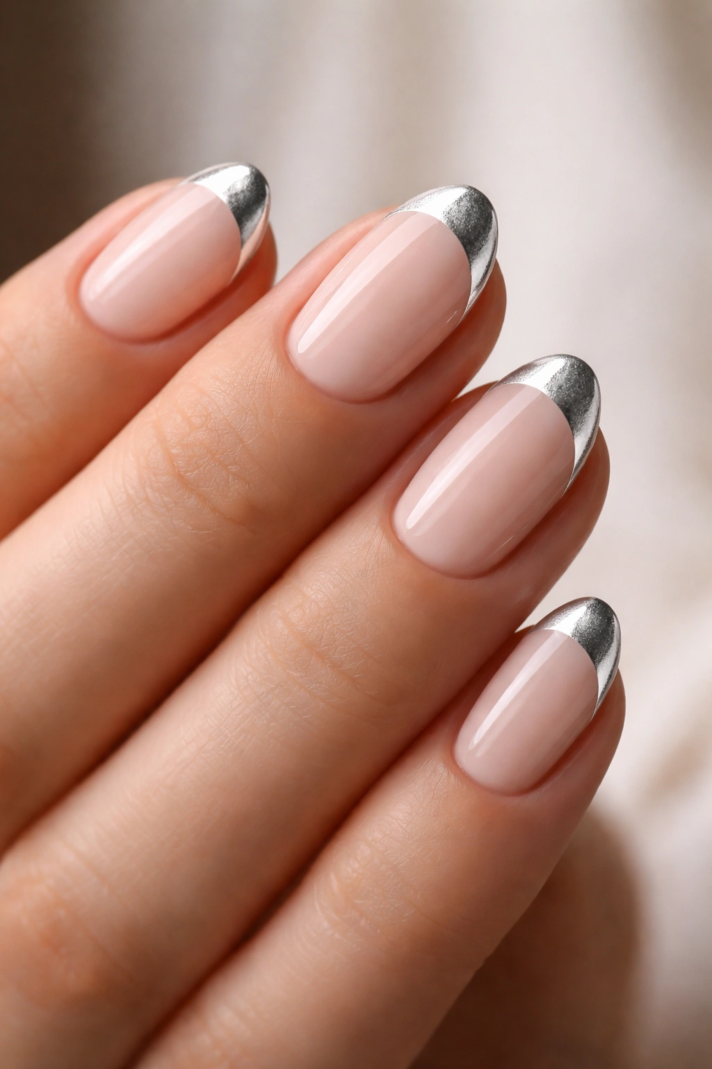Close-up of short almond nails with a silver half-moon at the cuticle