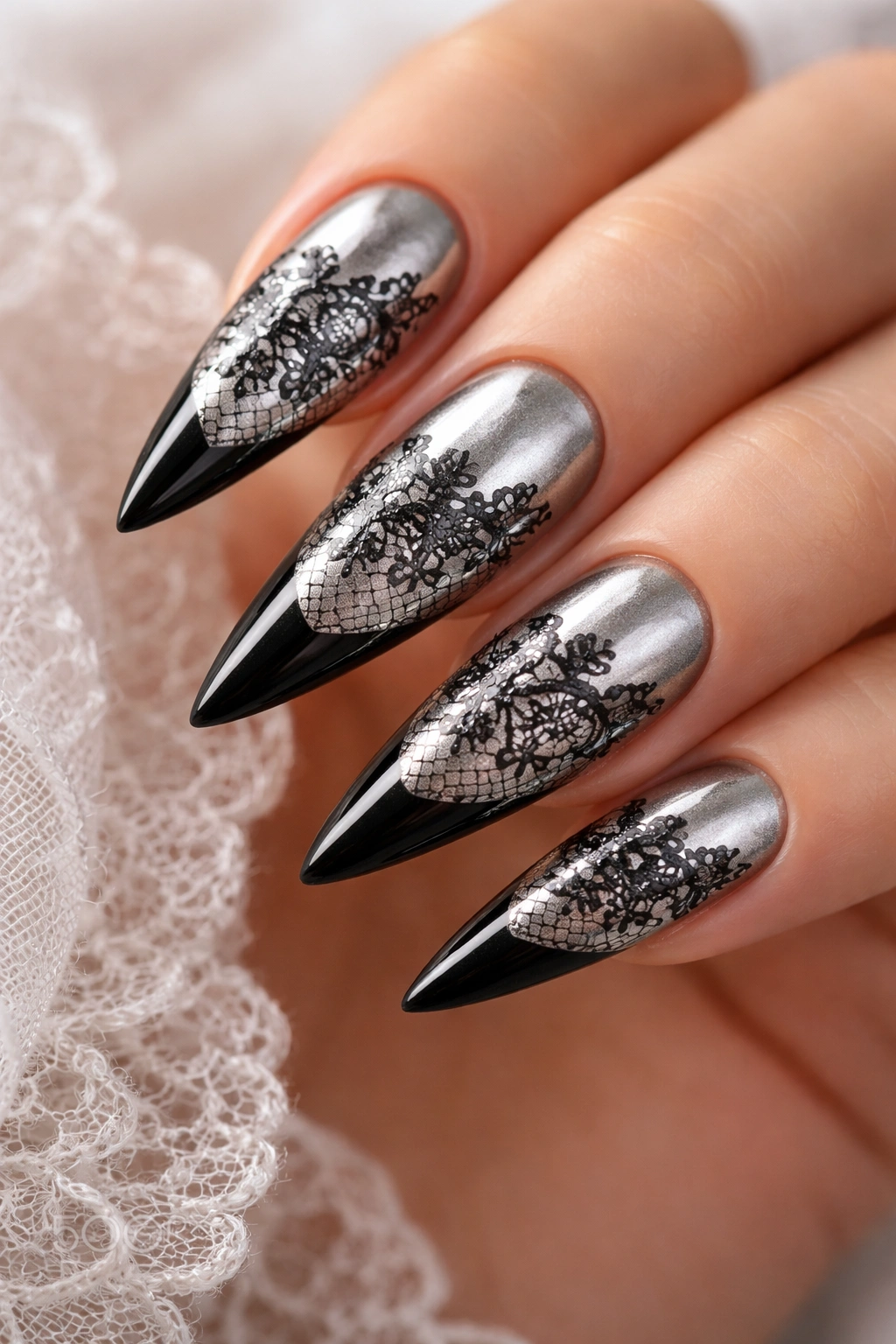 Close-up of silver-based stiletto nails with black lace detail and black tips