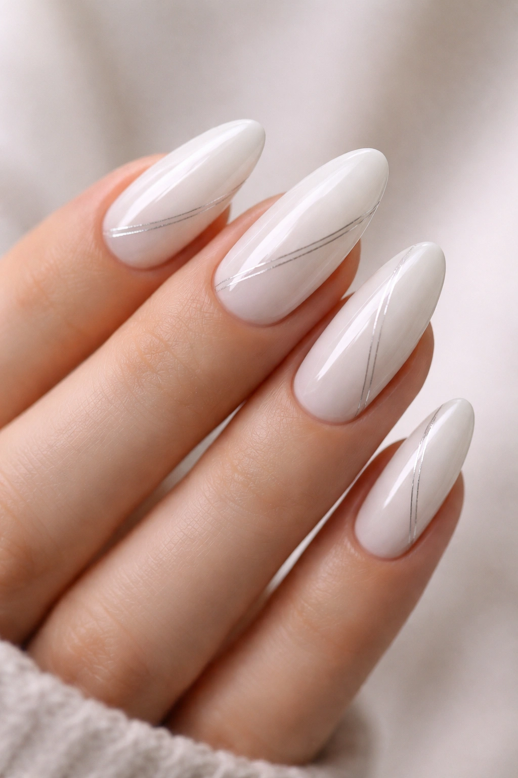 Almond nails with milky white base and thin silver lines