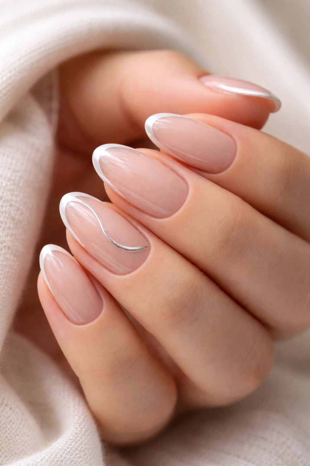 Close-up of short almond nails with a single ultra-thin silver line on a sheer nude base.