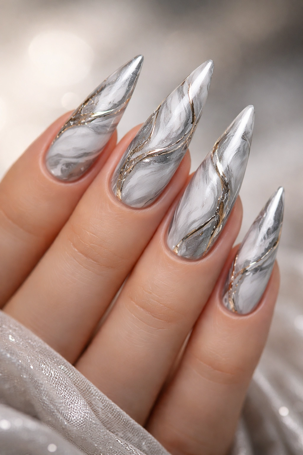 Close-up of silver marble nails with metallic veining on a bare hand
