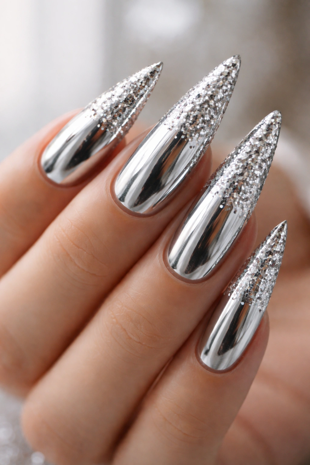 Stiletto nails with silver chrome mirror finish and scattered loose glitter