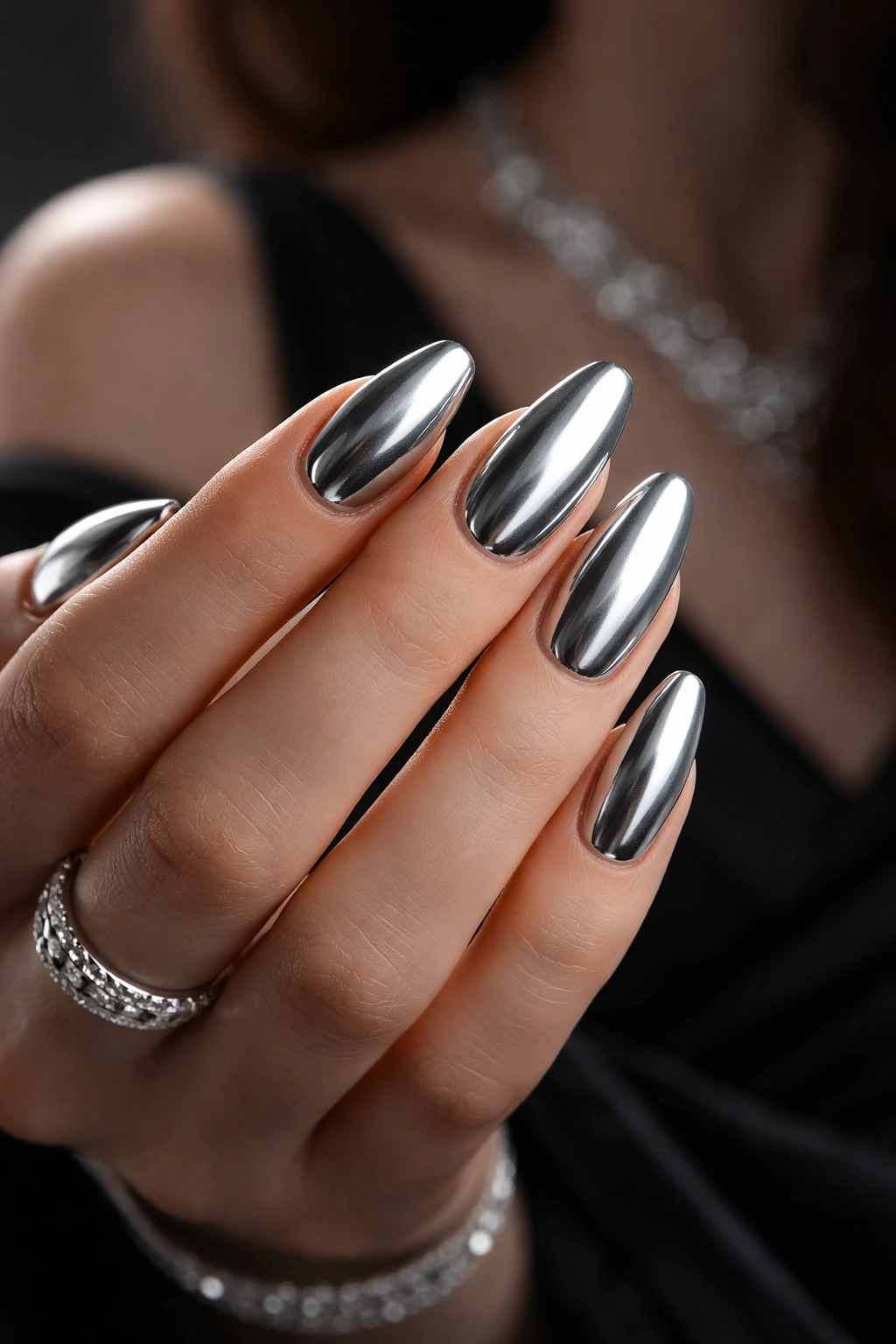 Close-up of cool silver chrome nails on a manicured hand with dark background