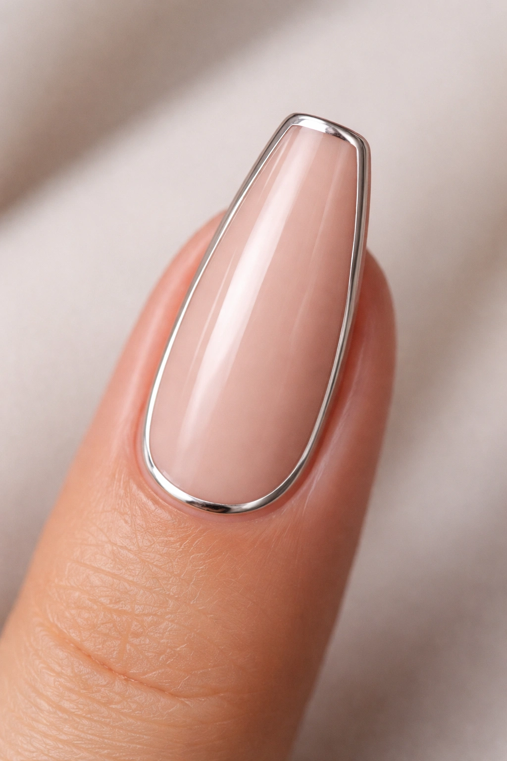 Close-up of a ballerina nail with a thin silver edge outline on nude center