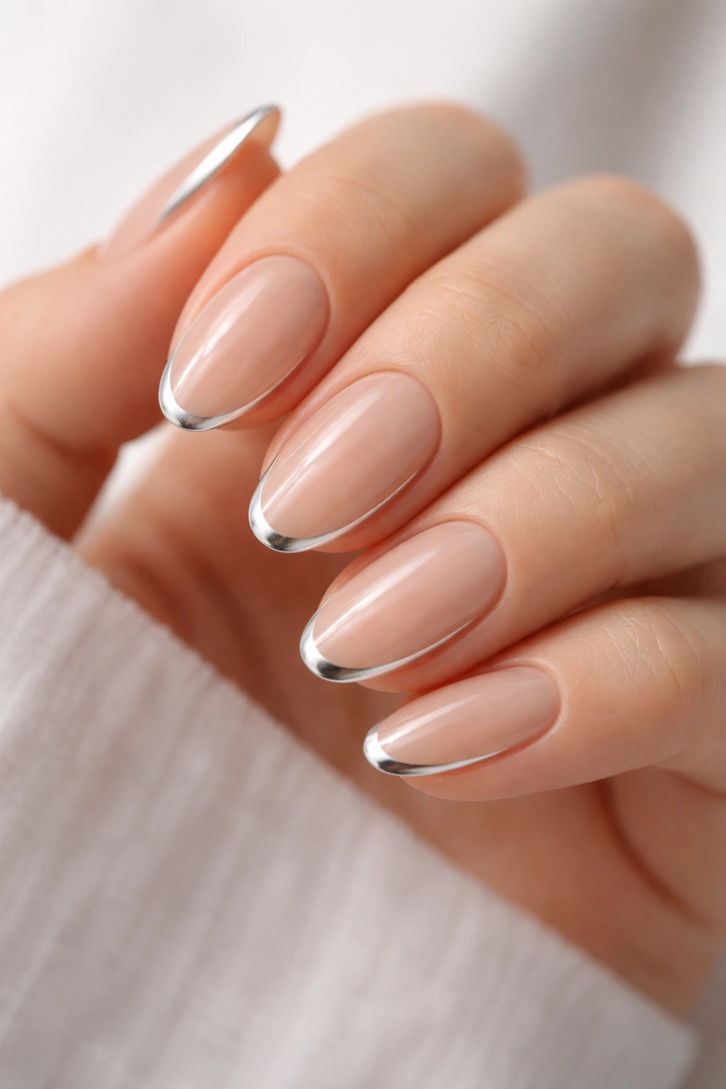 Close-up of short almond nails with a silver outline on a bare base